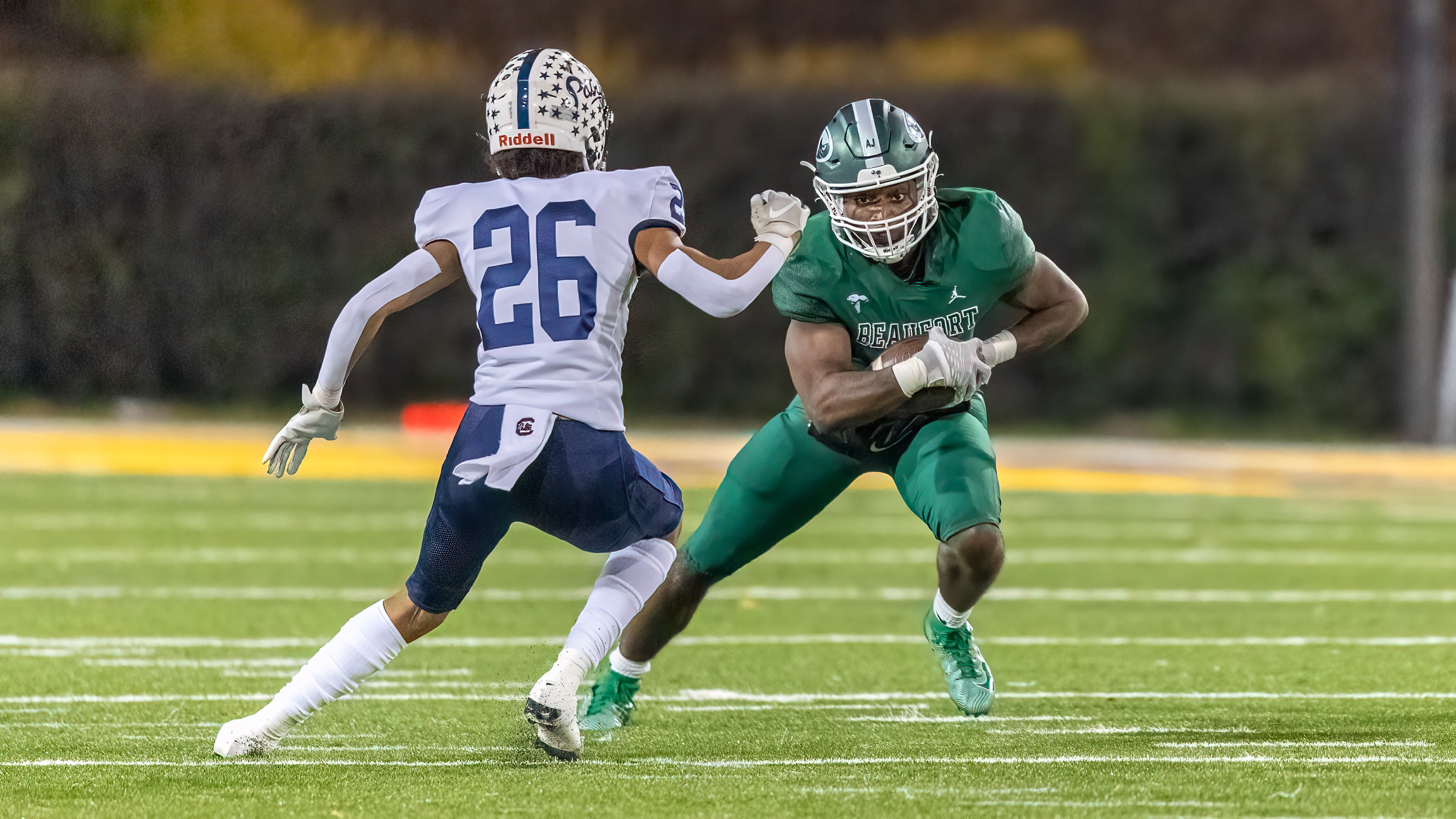 High school football players in green and white uniforms competing on the field during a game.